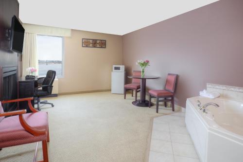 a room with a tub and a table and chairs at Travelodge by Wyndham Miramichi New Brunswick in Miramichi