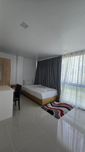 a bedroom with a bed and a window and a chair at joyful theKrisA205 in Ban Lum Fuang