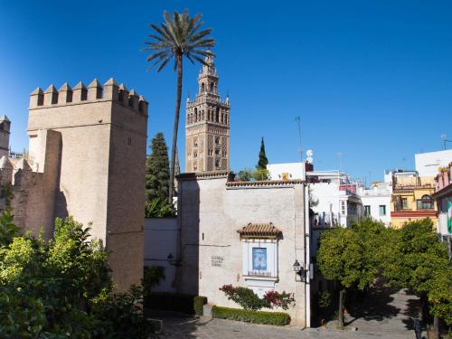 a building with a clock tower and a palm tree at Puerta Principe Luxury Apartments in Seville