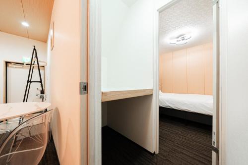 a small room with a bed and a room with a door at GLOU Akasaka Inn in Tokyo