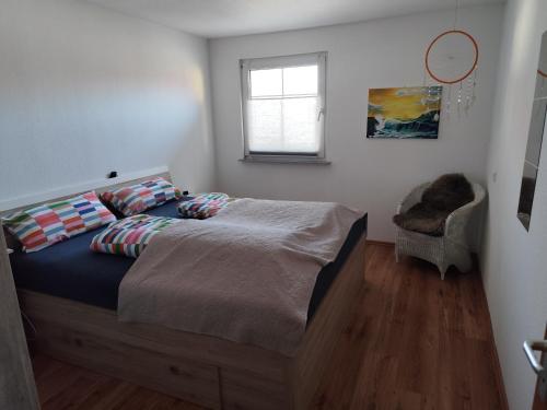 a bedroom with a bed and a window and a chair at Ferienwohnung am See in Ostrach