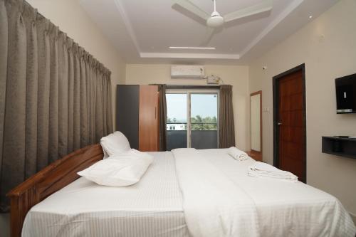 a bedroom with two beds with white sheets and a window at v square inn in Visakhapatnam