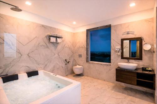 a bathroom with a tub and a toilet and a sink at The Colonial - A Lake View Hotel in Udaipur in Udaipur