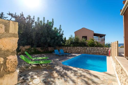 a swimming pool with two lawn chairs next to a house at Arto's Villa With Private Pool- BY APOKORONAS VILLAS in Plaka