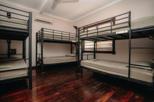 a room with three bunk beds and a wooden floor at Kimberley Travellers Lodge in Broome