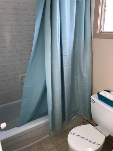 a bathroom with a blue shower curtain and a toilet at Motel Belle Riviere in Saint-Jean-sur-Richelieu