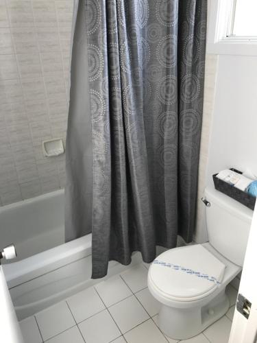 a bathroom with a toilet and a shower curtain at Motel Belle Riviere in Saint-Jean-sur-Richelieu