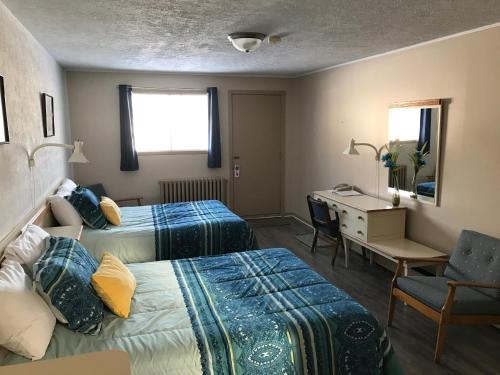 a hotel room with two beds and a desk and a chair at Motel Belle Riviere in Saint-Jean-sur-Richelieu