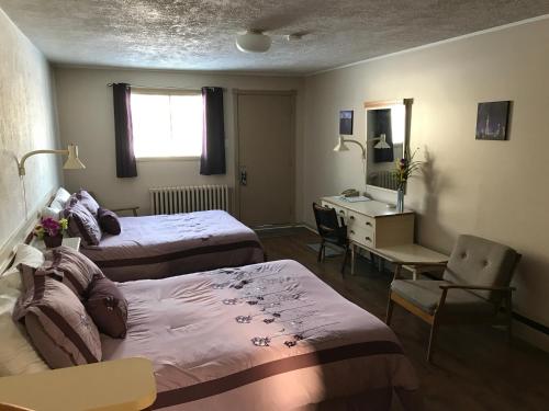 a hotel room with two beds and a desk and a mirror at Motel Belle Riviere in Saint-Jean-sur-Richelieu