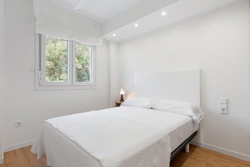 a white bedroom with a bed and a window at Bellavista Apartamento Marmen in Málaga