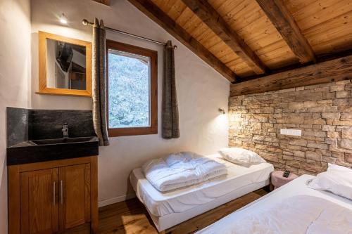 ein Schlafzimmer mit zwei Betten, einem Waschbecken und einer Ziegelwand in der Unterkunft Chalet Bordon in Champagny-en-Vanoise