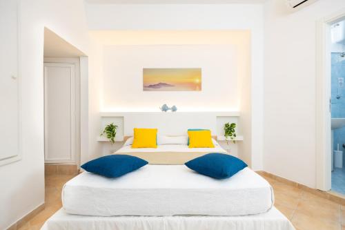 a white bedroom with a large bed with blue and yellow pillows at Birago22Capri in Capri