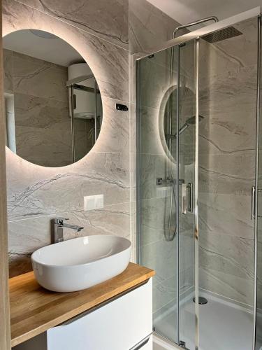 a bathroom with a sink and a glass shower at Czarnowodzianka domki w pierwszej linii brzegowej z widokiem na jezioro in Borsk
