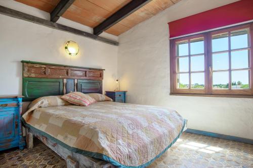 a bedroom with a bed with a wooden headboard and a window at Casa Azul - Vejer, El Palmar in Vejer de la Frontera