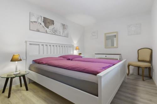 a white bedroom with a large bed and a chair at Casa Bianca in Offenburg