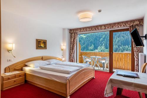 a bedroom with a bed and a balcony with a table at Hotel Residence Gardena Stevia 307 in Santa Cristina Gherdëina