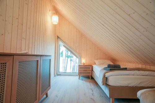 a attic bedroom with a bed and a window at Czarnowodzianka domki w pierwszej linii brzegowej z widokiem na jezioro in Borsk