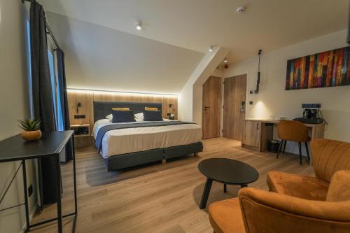 a bedroom with a bed and a living room at Hotel Le Charme de la Semois in Alle