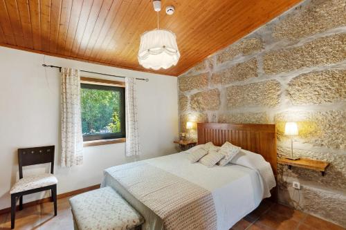 a bedroom with a bed and a stone wall at Casa de Andrães Camélias in Marco de Canaveses