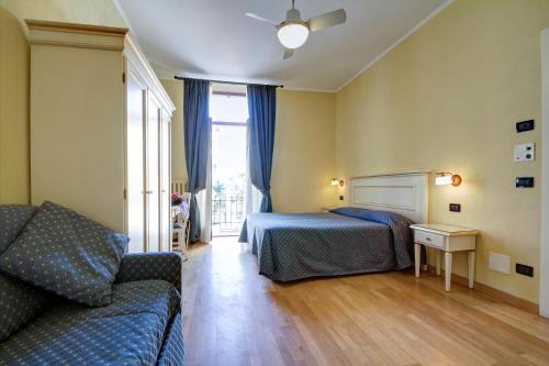 a bedroom with a bed and a couch and a window at Hotel Primula in Alassio