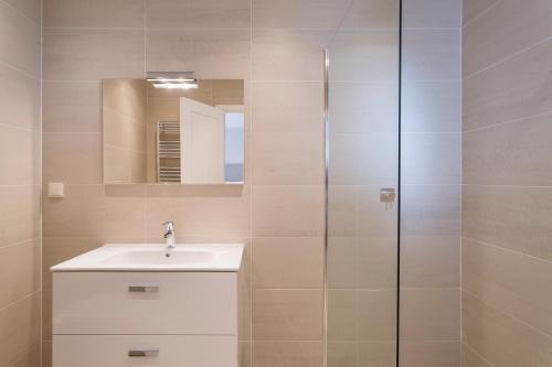 a bathroom with a sink and a glass shower at Villa Leeroy in Almancil