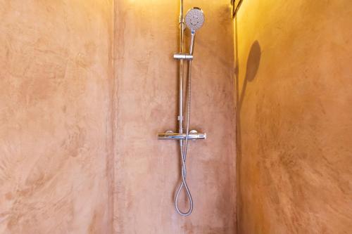 a shower with a shower head on a wall at Dependance avec Jacuzzi in Arcangues