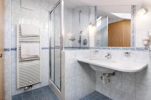 a white bathroom with a sink and a shower at Haus Peer Burgeis in Malles Venosta