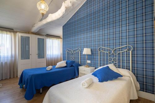 a bedroom with two beds and a blue wall at Apartamento La Calleja in Arzúa
