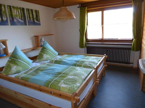 a bedroom with a bed with a green comforter and a window at Ferienhaus am Bach in Wieden
