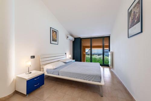 a white bedroom with a bed and a window at Nice apartment Le Vele Garda Lake in Toscolano Maderno