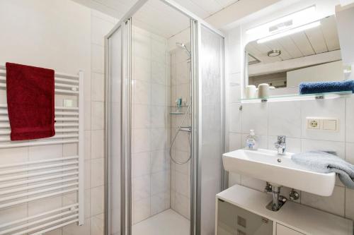 a white bathroom with a shower and a sink at Ferienhaus Reetkate Breklum in Breklum