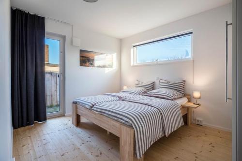 a bedroom with a bed with striped sheets and two windows at Ferienhaus Spaden in Spaden