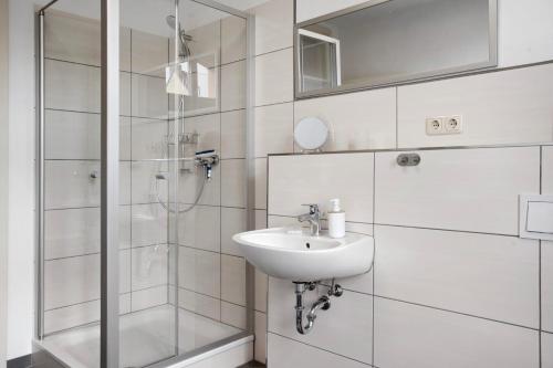 a white bathroom with a sink and a shower at Alte Seifensiederei 3 in Stralsund