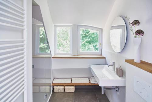 a white bathroom with a sink and two windows at Große Atelierwohnung Barrierefrei in Meezen