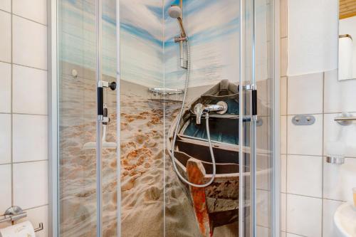 a bathroom with a shower with a painting of a boat at Ferienhaus Landhaus Loose in Schashagen