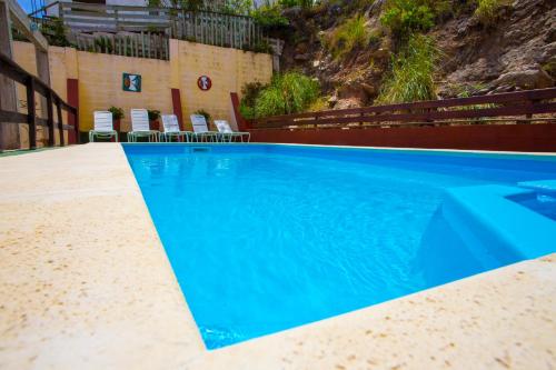 a blue swimming pool with chairs next to a building at San Remo Terrazas Hotel in Piriápolis