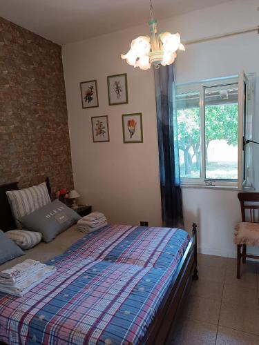 a bedroom with a bed and a window and a chandelier at Casetta Esmeralda in Praia a Mare