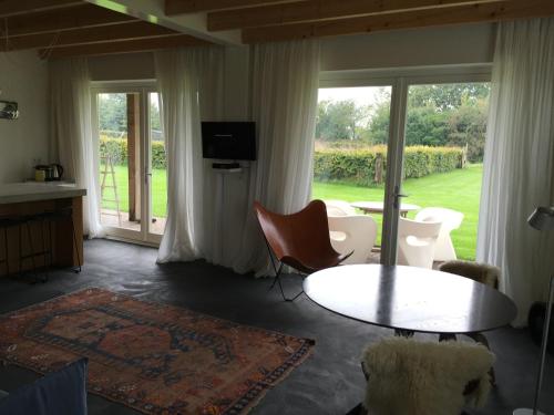 sala de estar con mesa, sillas y puertas correderas de cristal en Huisje Wevers, en Bathmen