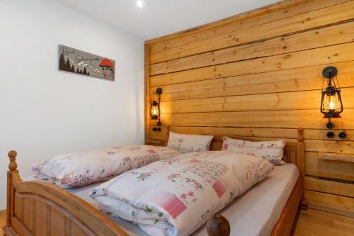 two beds in a bedroom with a wooden wall at Müllerleile Hof in Haslach im Kinzigtal
