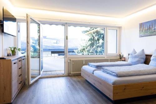 two beds in a room with a large window at Höri-Nest Abendsonne-Appartement in Gaienhofen