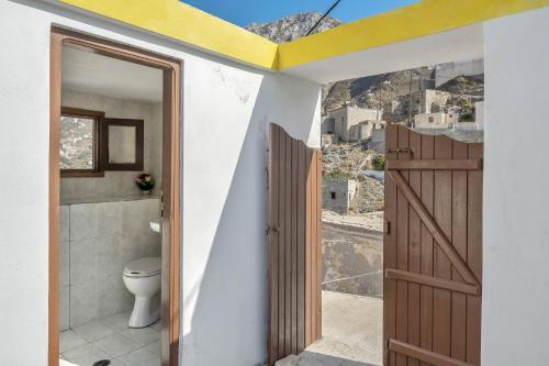 a bathroom with a toilet and a wooden door at Villa Houvarda in Karpathos