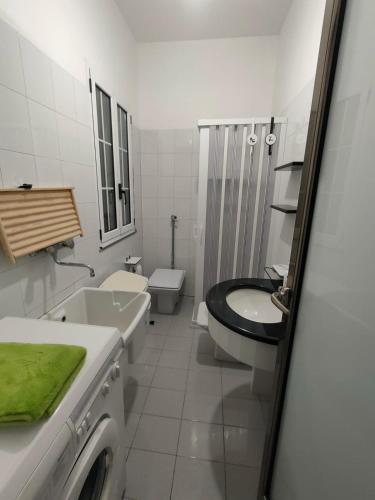 a white bathroom with a sink and a toilet at Villetta Roby in Marina di Modica