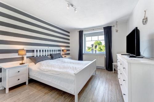 a bedroom with a white bed and a flat screen tv at Alte Schule Schalkholz in Schalkholz