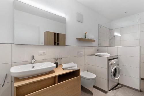 a bathroom with a sink and a washing machine at Ferienwohnung Rebenrain, 80qm in Steinach