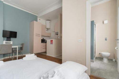 a bedroom with a white bed and a kitchen at GuestHost - Chic Flat Steps from Duomo in Milan