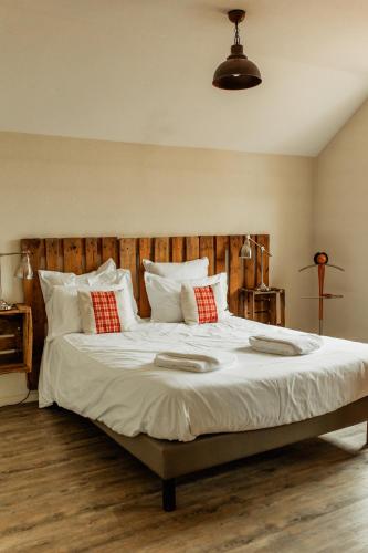 a large bed with white sheets and red pillows at L'éclos des vignes - Appartements haut de gamme avec Spa in Bergheim