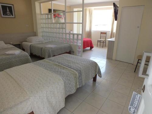 a hotel room with three beds in a room at Hostal Gazu in Chiclayo