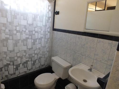 a bathroom with a white toilet and a sink at Hostal Gazu in Chiclayo