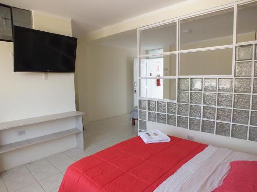 a bedroom with a red bed and a flat screen tv at Hostal Gazu in Chiclayo