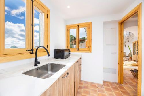 a kitchen with a sink and some windows at Can Titina in Puigpunyent